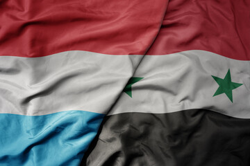big waving national colorful flag of syria and national flag of luxembourg .