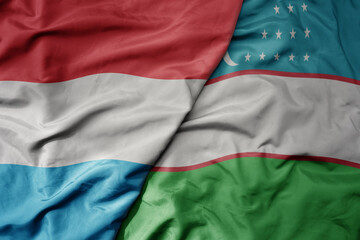 big waving national colorful flag of uzbekistan and national flag of luxembourg .