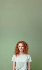 Happy positive smiling attractive redheaded teenage girl with curly hair looking at camera wearing casual trendy t-shirt standing isolated on green background over studio copy space background.