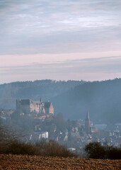 Fototapeta premium Nebelmorgen Teleblick zum Schloß Marburg, Wälder und Ort