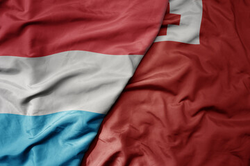 big waving national colorful flag of Tonga and national flag of luxembourg .