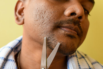 An Indian male grooming and beautifying his beard and mustache with a small scissors. Selective...