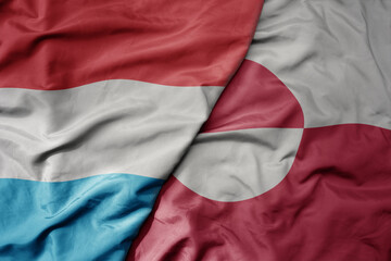 Fototapeta premium big waving national colorful flag of greenland and national flag of luxembourg .