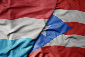 big waving national colorful flag of puerto rico and national flag of luxembourg .