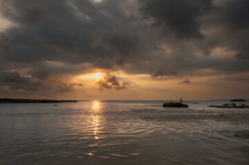 Fototapeta premium Puesta de sol con bonitos colores con figura de pescador en distintas zonas en la playa de Ujung Genteng, Sukabumi, Java, Indonesia