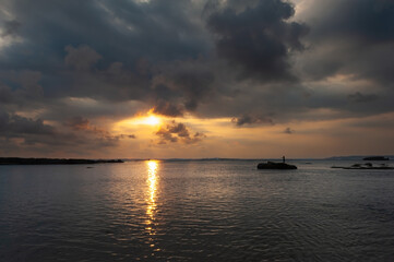 Fototapeta premium Puesta de sol con bonitos colores con figura de pescador en distintas zonas en la playa de Ujung Genteng, Sukabumi, Java, Indonesia