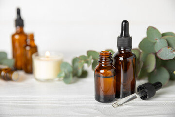 Eucalyptus essential oil in a glass bottle with green eucalyptus leaves on a textured wooden background. Aromatherapy concept. Spa. Natural organic ingredients for cosmetics and body care.Copy space