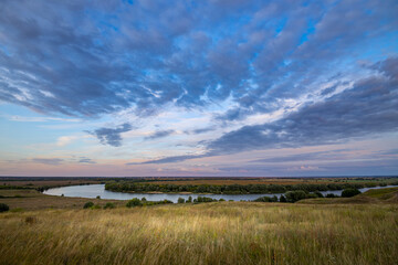 Fototapeta premium Epic views of vast expanses of fields, the bend of a wide river and rolling hills of meadow grass.