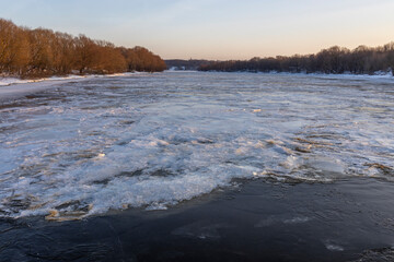 Ice floats on the water, frosty evening, cold, winter landscape with a wide river.