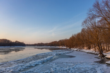 Ice floats on the water, frosty evening, cold, winter landscape with a wide river.