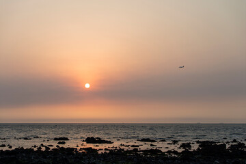 View of the sunset with a flying airplane