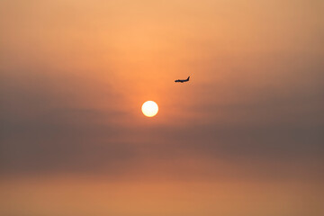 View of the sunset with a flying airplane