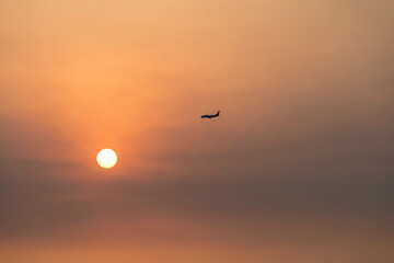 View of the sunset with a flying airplane