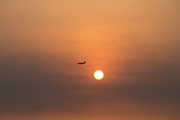 View of the sunset with a flying airplane