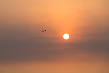 View of the sunset with a flying airplane
