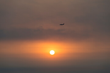 View of the sunset with a flying airplane