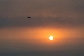 View of the sunset with a flying airplane