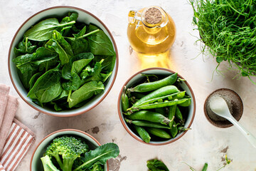 Fresh spinach leaves, green peas, broccoli in a bowl, top view