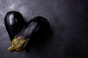 Composition of two eggplants on a dark background.