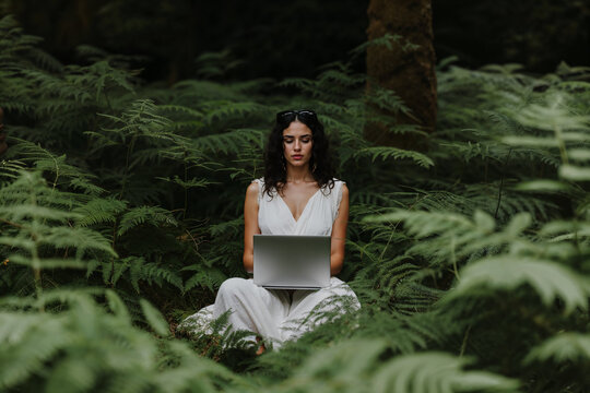 Young Woman Working on Laptop in Forest. Generative AI.