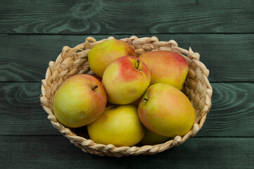 redsided apples in a wicker basket on a wooden background. sweet yellow apples on a blue texture	