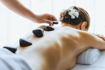 Hot stone massage at spa salon in luxury resort with day light serenity ambient, blissful woman...