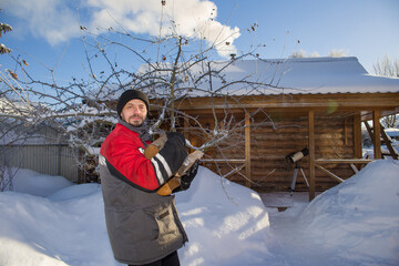 A man carries firewood to light the stove in the bathhouse.