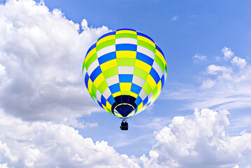 Colorful hot air balloon flying over blue sky with white clouds	
