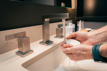 close up of man washing hands with soap in a hotel bathroom sink