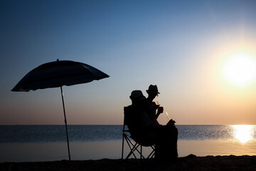 Fototapeta premium A Happy couple by the sea at sunset on travel silhouette in nature