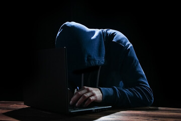 A Hacker with laptop sits at a table and abstract binary code. Business life threat virtual...