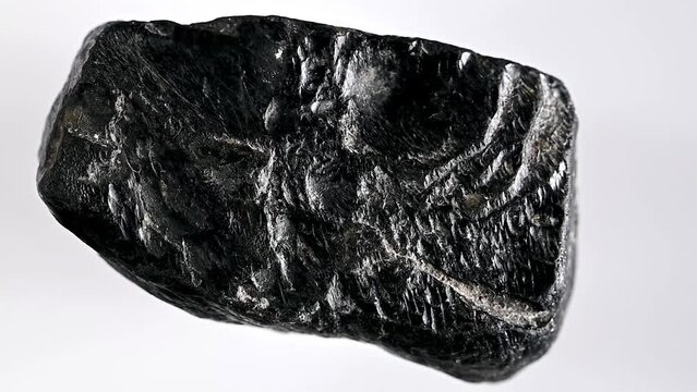 Black Obsidian (from Mexico) Natural volcanic glass, sample rotating slowly against a white background.	