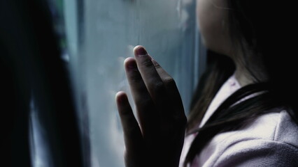 Obraz premium One depressed child leaning on glass window feeling sad and lonely at home, one small introspective girl depicitng childhood mental illness