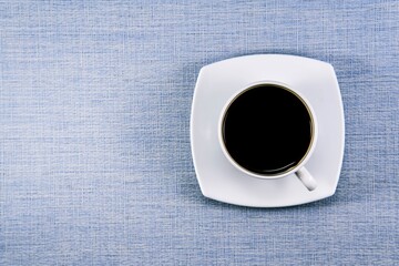 White cup of black coffee on the table. View from above.
