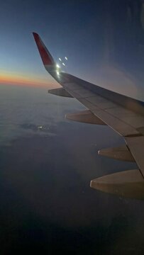Looking through window aircraft during flight in wing with a nice blue sky. flight and travel, view from the window of an airplane on the early morning. Vertical footage