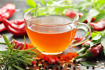 Tea with red chilli pepper spicel, tincture, extract or vinegar with fresh vegetables and leaves on black table, closeup, copy space, organic spicy food, hair and body healthy care concept
