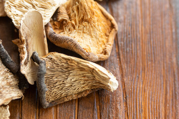A pile of forest aromatic edible dried mushrooms on a wooden dark background.