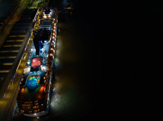 Aerial view of colorful top deck lights with swimming pool on a cruise ship before departure. Lights reflection on the dark sea. Illuminated cruise ship passenger terminal in Southampton, UK.