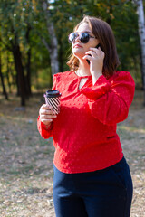 Woman in red blouse and with a mug of coffee talking on the phone