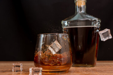 Ice cubes falling into a glass of whiskey