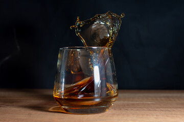 Splashes of cognac in a glass on a dark background