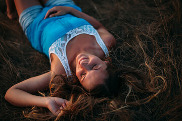 The girl lies on the straw with her eyes closed. The hair is scattered on the grass. The right hand...