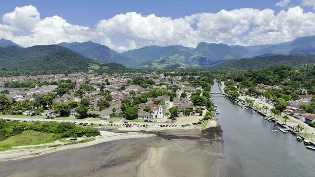 Aerial shot drone flies over shallow waters to colonial town between mountains and sea