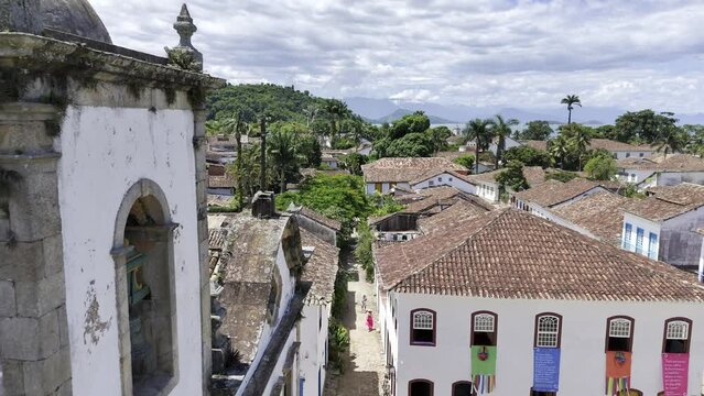 Aerial shot drone flies backwards with church facade on left and rest of town in front