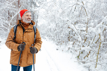 Mature caucasian man in red hat on a snowy background looking contented