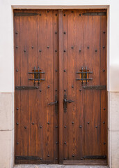 An old wooden door with forged handles and forged hinges, small viewing windows with bars....