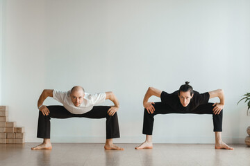 two young athletes practice yoga in the gym. Joint training, indoors, studio. The concept of a...