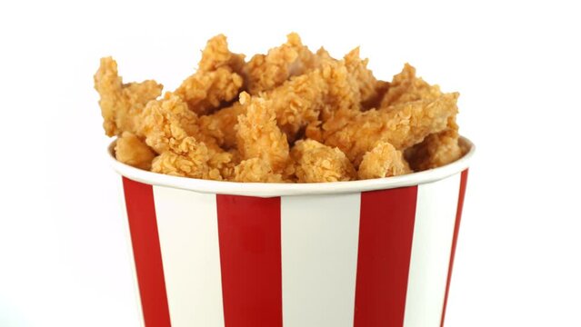 Slow Motion of Rotating Fried Chicken Pieces in Bucket, isolated on white background. Fresh Crispy Chicken with smoke, Rotating on Turntable. Speed Ramp Effect.