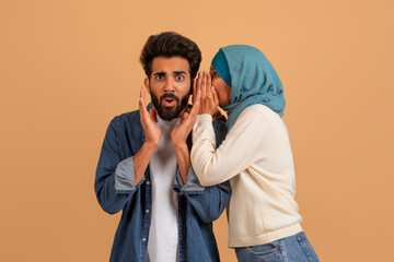 Sharing Secret. Muslim Woman In Hijab Whispering To Shocked Husbands Ear