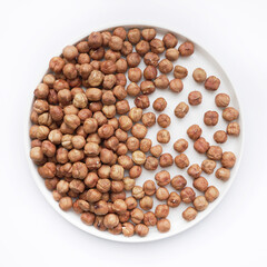 A bounty of hazelnuts fills a white plate, their warm brown tones and round shapes creating a pleasing pattern. These nuts are a delicious source of healthy fats and vitamins.